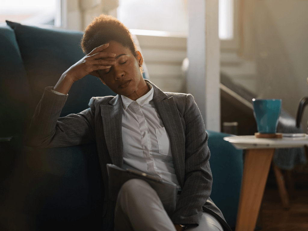 Exhausted businesswoman holding her head, coping with daily stress and mental strain.